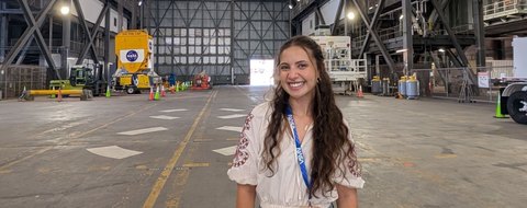 Payton Barnwell on the floor of the Vehicle Assembly Building at Kennedy, the Artemis banner behind her.