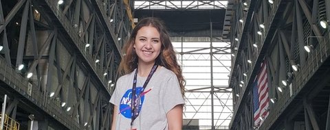 Payton Barnwell inside the Vehicle Assembly Building at Kennedy Space Center, NASA badge around her neck.